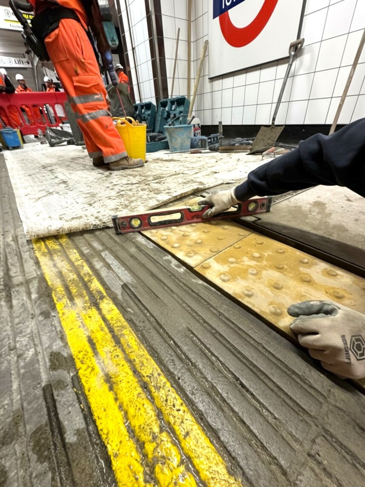 Spirit level checking new tactile paving on a station platform